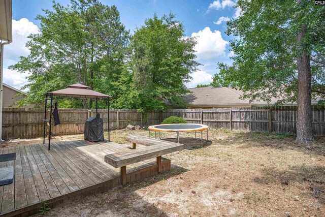 view of yard with a gazebo, a fenced backyard, a trampoline, and a deck
