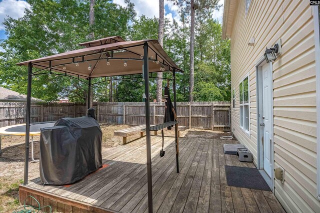 deck featuring a fenced backyard, a gazebo, and a grill