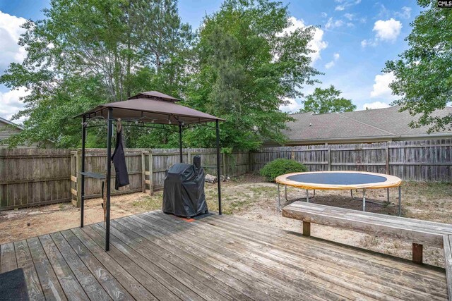 deck with a gazebo, a fenced backyard, and a trampoline