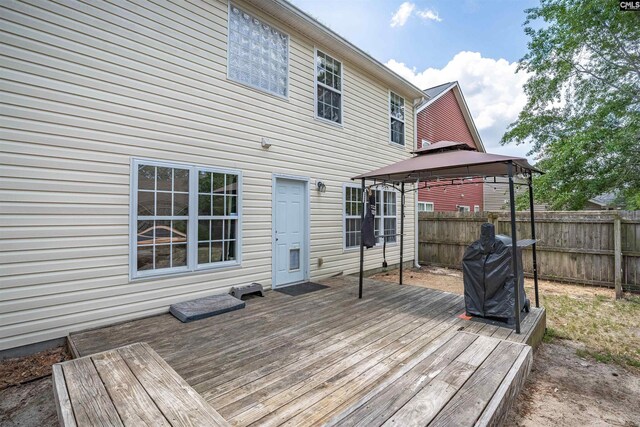 wooden terrace with grilling area, a gazebo, and fence