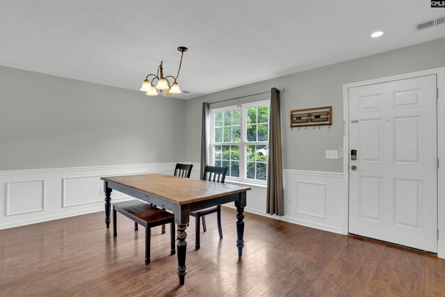dining room with visible vents, a wainscoted wall, a notable chandelier, a decorative wall, and dark wood-type flooring