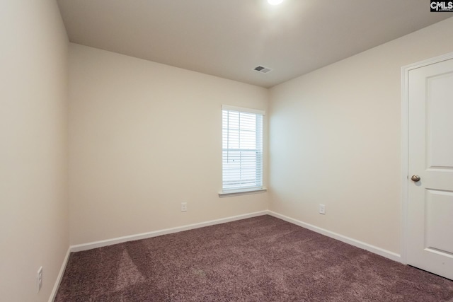unfurnished room with visible vents, baseboards, and dark carpet