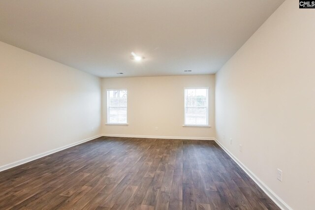 spare room with baseboards, a healthy amount of sunlight, and dark wood finished floors