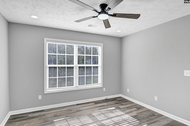 spare room featuring visible vents, wood finished floors, baseboards, a textured ceiling, and a ceiling fan