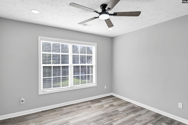 spare room featuring a ceiling fan, a textured ceiling, a healthy amount of sunlight, and wood finished floors