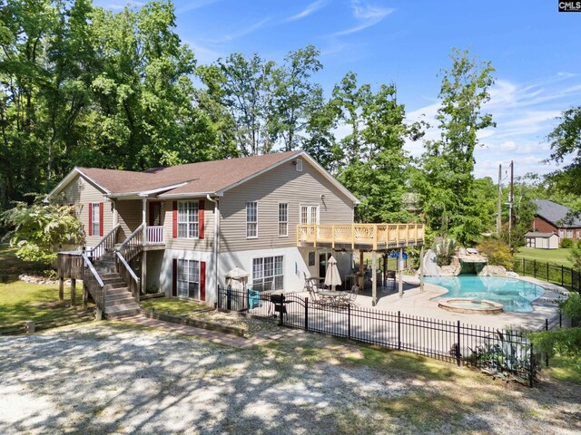rear view of property with a deck, a patio, a fenced backyard, a fenced in pool, and a gate