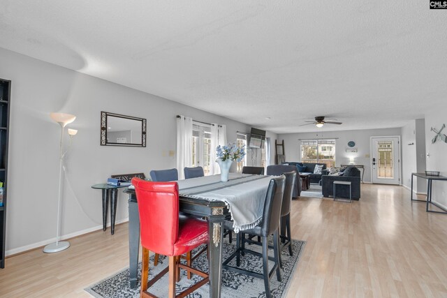 dining room featuring light wood-style floors, a ceiling fan, a textured ceiling, and baseboards