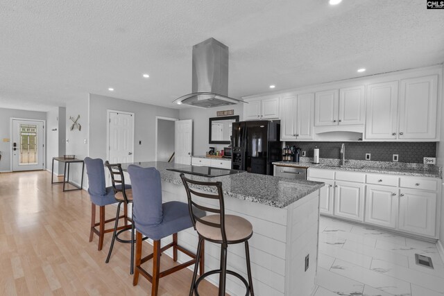 kitchen featuring white cabinets, a textured ceiling, island range hood, a kitchen island, and black appliances
