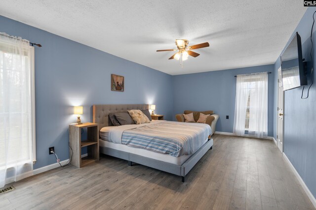 bedroom with a textured ceiling, baseboards, and wood finished floors