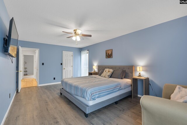 bedroom featuring a ceiling fan, baseboards, and wood finished floors