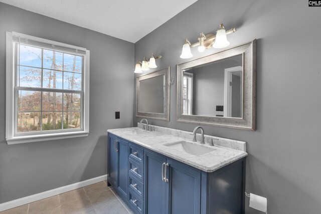 bathroom with double vanity, baseboards, a sink, and tile patterned flooring