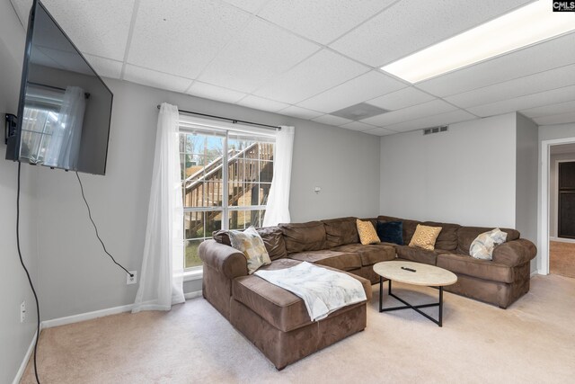carpeted living area with baseboards, a drop ceiling, and visible vents