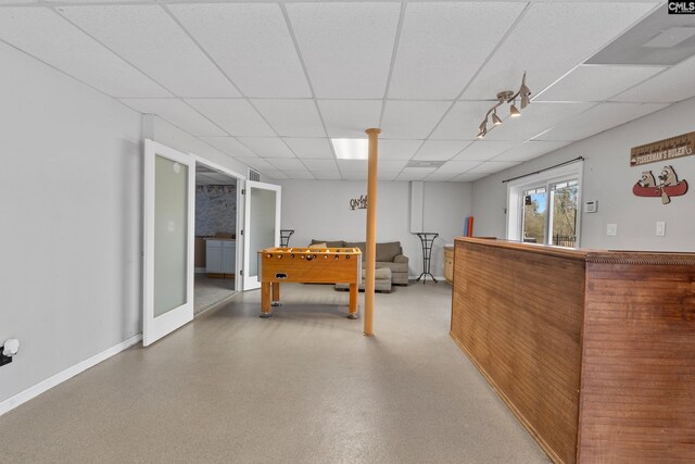 recreation room featuring baseboards and a paneled ceiling
