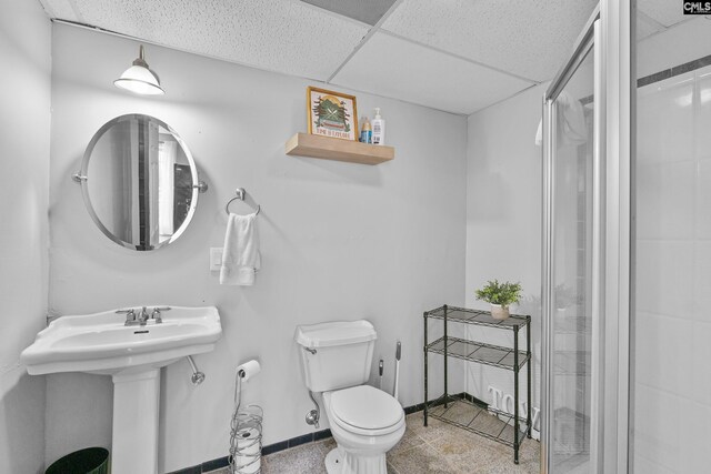 bathroom with toilet, baseboards, a shower stall, and a sink