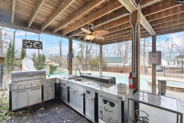 view of patio / terrace featuring fence, an outdoor kitchen, area for grilling, a fenced in pool, and a sink