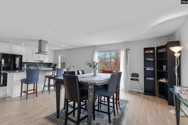 dining space with recessed lighting, a textured ceiling, and light wood-type flooring