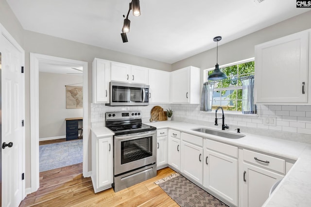 kitchen with light wood-type flooring, light countertops, white cabinetry, a sink, and stainless steel appliances