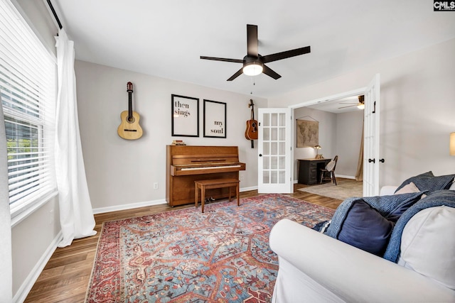 living area with a ceiling fan, baseboards, french doors, and wood finished floors