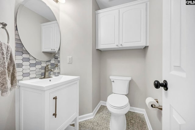 half bath featuring vanity, tasteful backsplash, baseboards, and toilet
