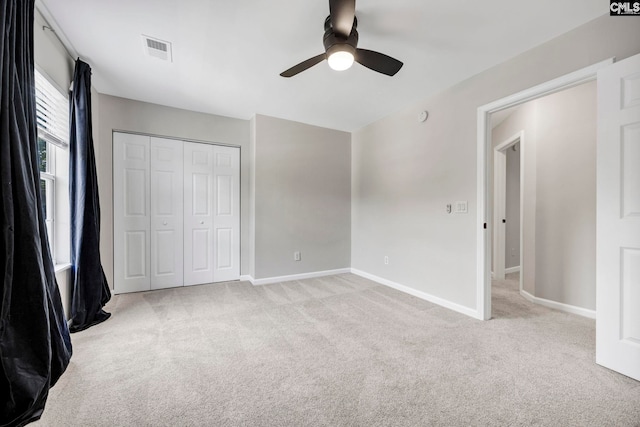 unfurnished bedroom with visible vents, a closet, light carpet, baseboards, and ceiling fan