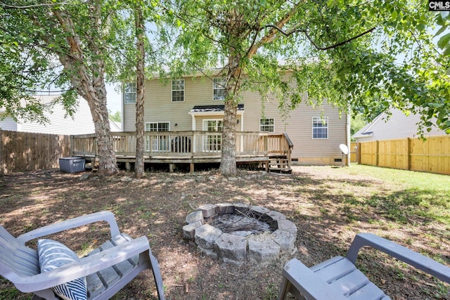 rear view of property featuring a fenced backyard, a wooden deck, a fire pit, and crawl space