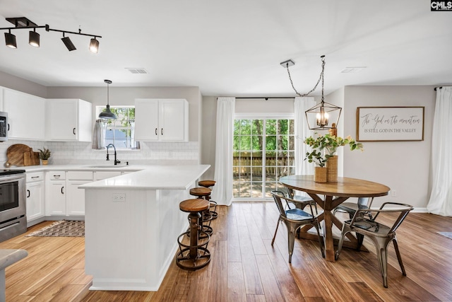 kitchen with decorative backsplash, electric range, visible vents, a sink, and light countertops
