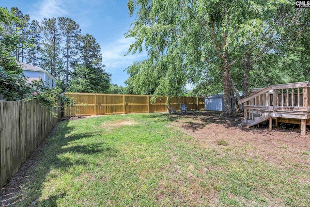 view of yard with a deck, an outbuilding, a shed, and a fenced backyard