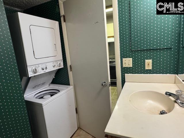 bathroom featuring stacked washer / drying machine, a sink, and tile patterned flooring