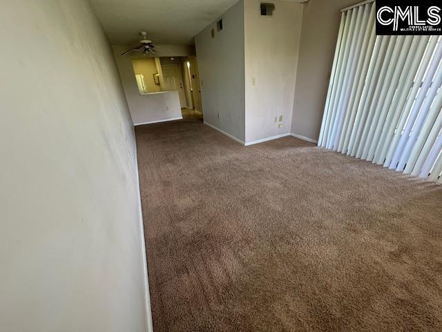 carpeted spare room featuring baseboards and a ceiling fan