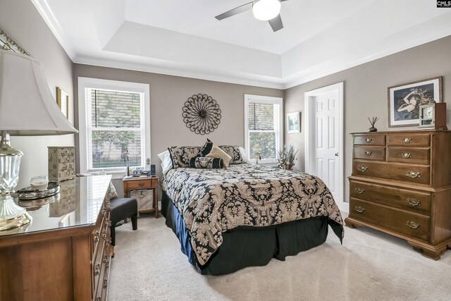 bedroom featuring crown molding, a ceiling fan, a tray ceiling, and light carpet