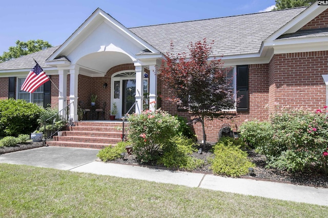 view of exterior entry with a porch and brick siding