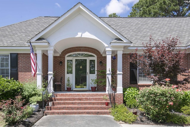 view of exterior entry with covered porch and brick siding