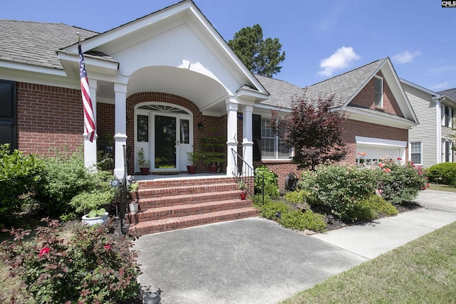 entrance to property featuring covered porch and brick siding