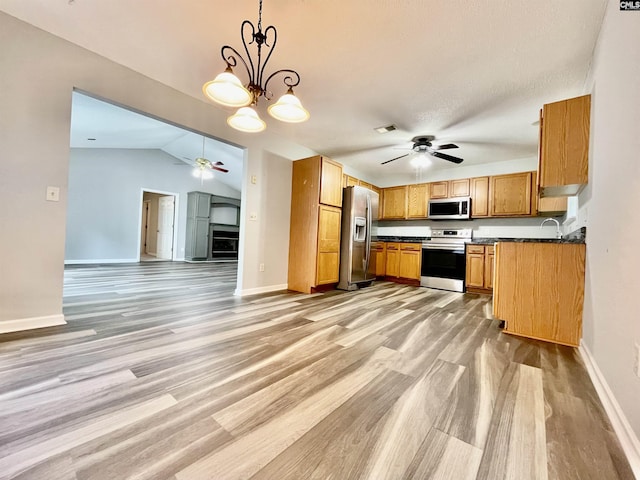kitchen with appliances with stainless steel finishes, baseboards, ceiling fan with notable chandelier, and light wood finished floors