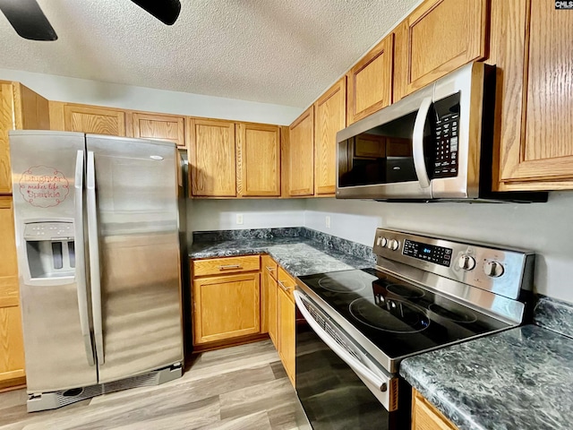 kitchen featuring light wood-style floors, appliances with stainless steel finishes, a ceiling fan, and a textured ceiling