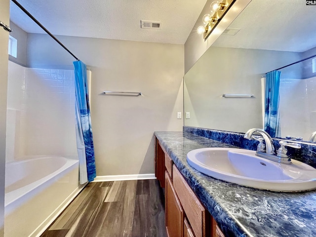 bathroom featuring a textured ceiling, visible vents, wood finished floors, vanity, and shower / bathtub combination with curtain