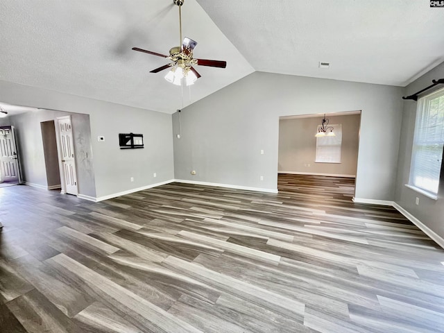 unfurnished living room with visible vents, wood finished floors, baseboards, ceiling fan with notable chandelier, and vaulted ceiling