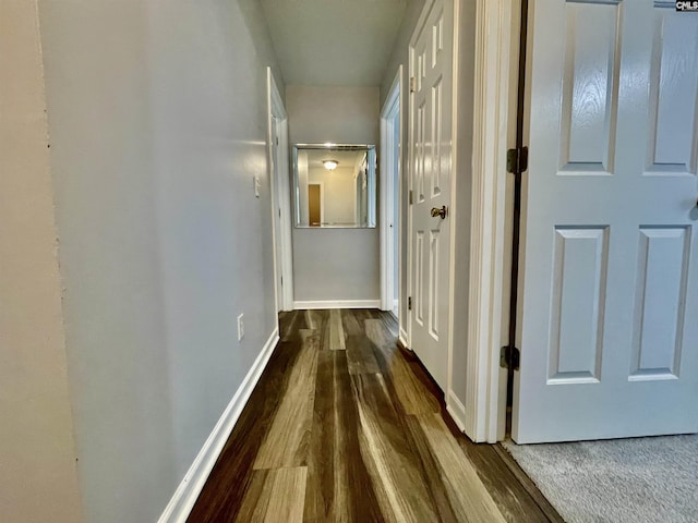 hall featuring baseboards and dark wood-style flooring