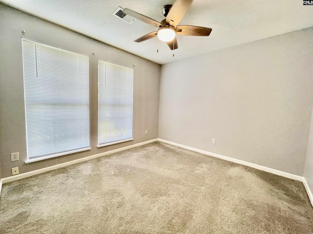 carpeted spare room featuring baseboards, ceiling fan, and visible vents
