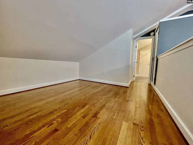 additional living space with wood finished floors, baseboards, and lofted ceiling