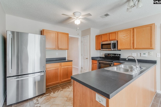kitchen with visible vents, a peninsula, ceiling fan, a sink, and stainless steel appliances