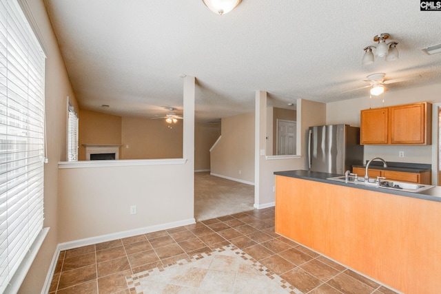 kitchen featuring light tile patterned flooring, dark countertops, a sink, freestanding refrigerator, and a ceiling fan
