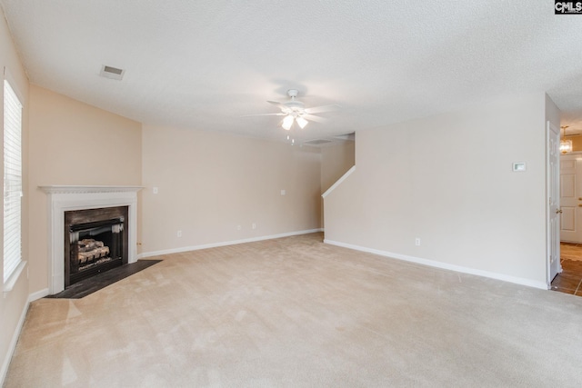 unfurnished living room featuring carpet floors, ceiling fan, a fireplace with flush hearth, and baseboards