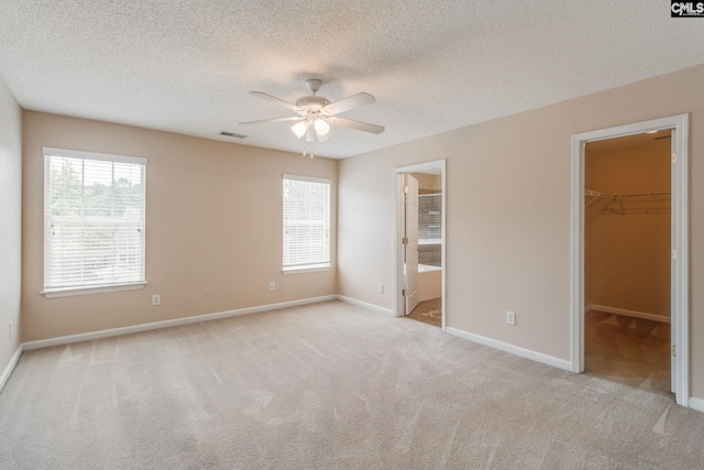 unfurnished bedroom featuring carpet floors, visible vents, baseboards, and a spacious closet