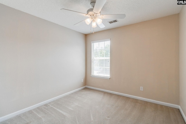 spare room featuring a ceiling fan, baseboards, visible vents, and light carpet