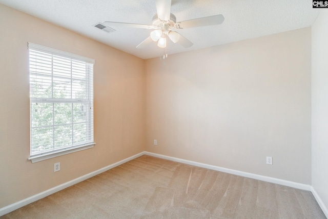 unfurnished room with visible vents, a ceiling fan, baseboards, and light carpet