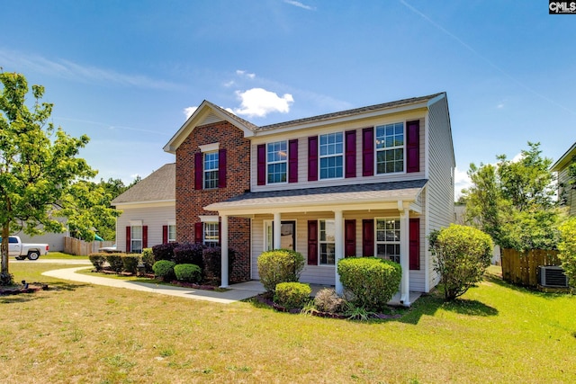 traditional-style home featuring a porch, a front lawn, fence, and cooling unit