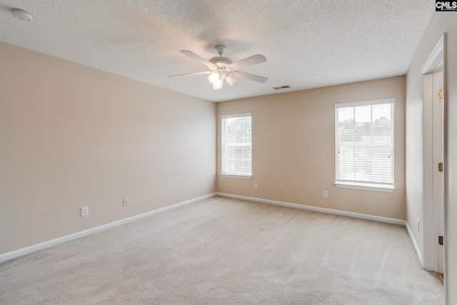 spare room with a ceiling fan, a textured ceiling, visible vents, and light colored carpet