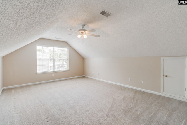 bonus room featuring a ceiling fan, a textured ceiling, visible vents, and light colored carpet