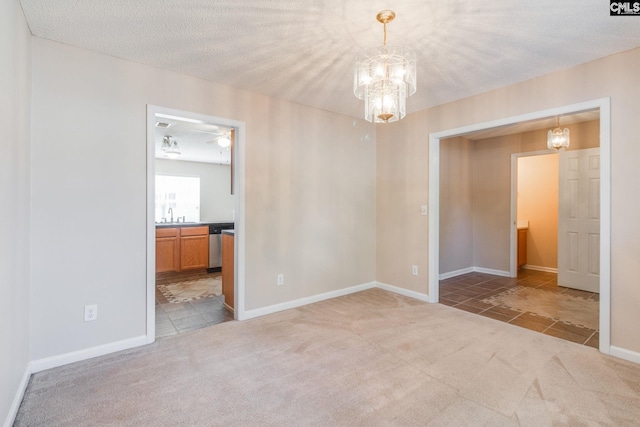 carpeted empty room featuring tile patterned floors, a chandelier, and a sink